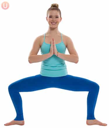Chloe Freytag demonstrating Horse Pose in a blue tank top and yoga pants