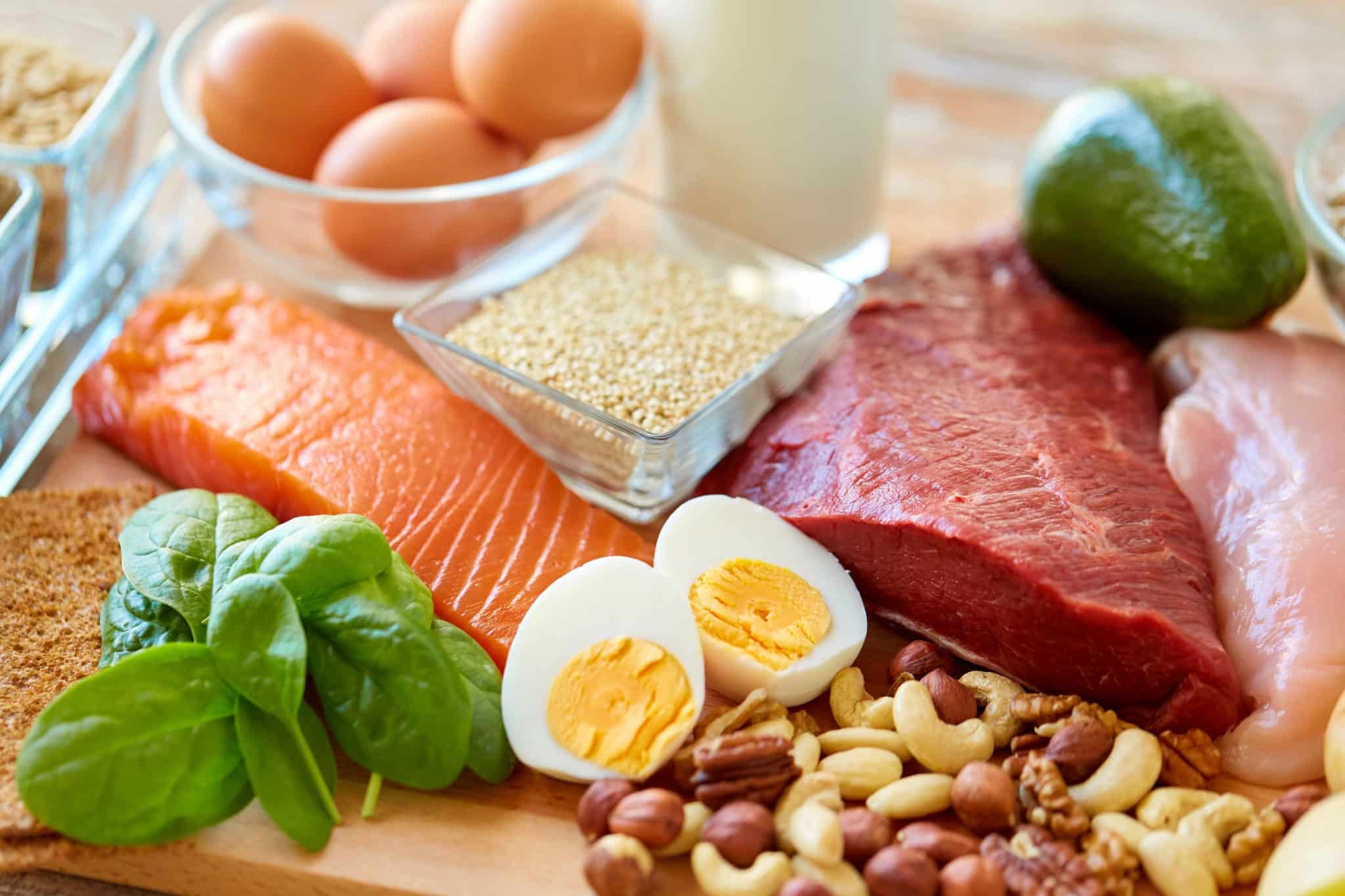 High-protein foods such as salmon, eggs, nuts, red meat, etc. on a table