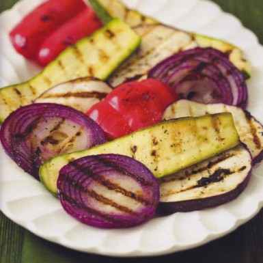a white plate filled with grilled, onion, zucchini. and peppers