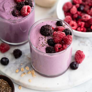 two servings of healthy mixed berry smoothie with toppings