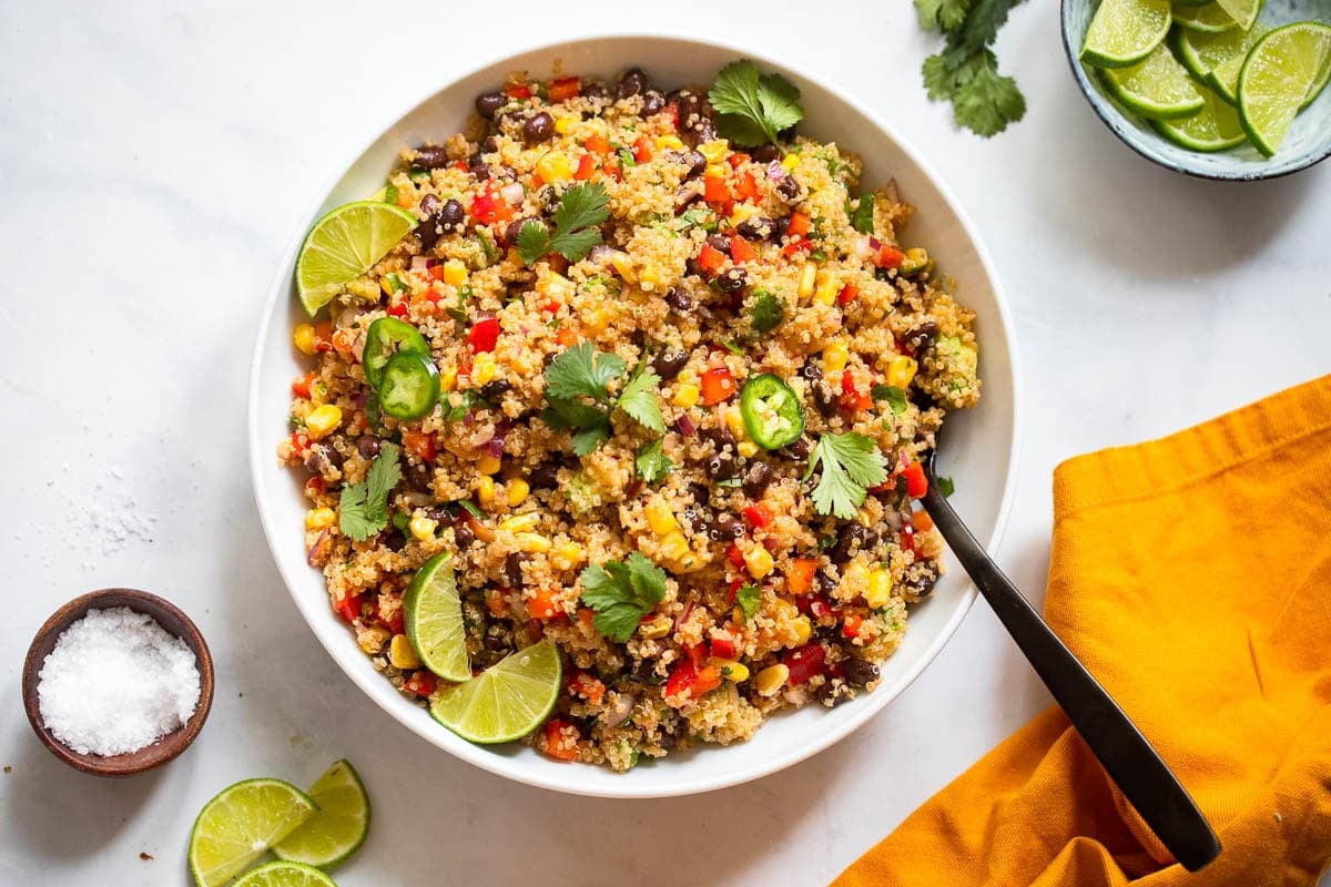single southwest quinoa salad serving in white bowl with fork on white countertop background