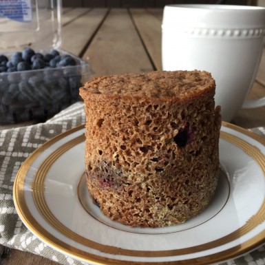 A mug muffin with blueberries sitting on a plate