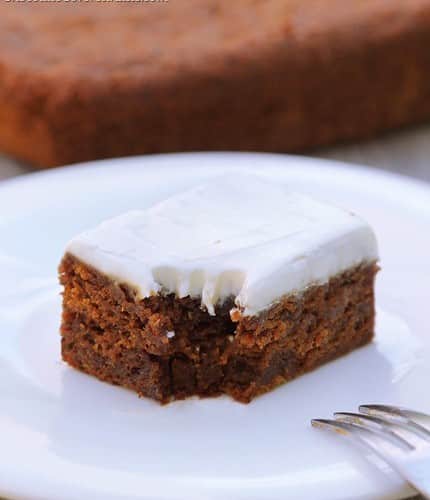 A slice of Homemade Gingerbread on a white plate with a fork next to it.
