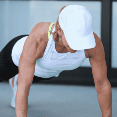 Chris Freytag doing a push up with white hat, white tank and black leggings