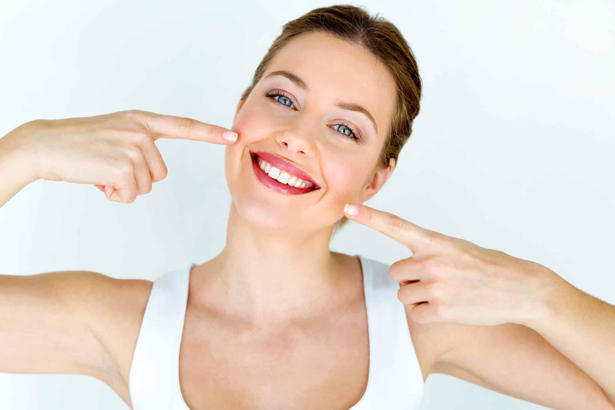 Woman smiling and pointing to white teeth