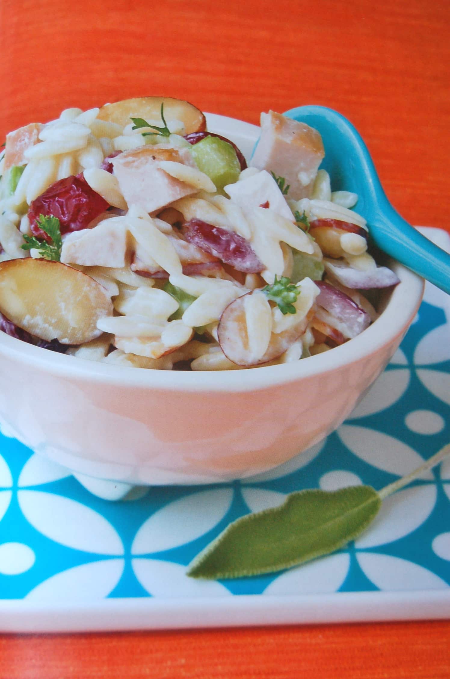 A white bowl filled with creamy orzo salad with cherries and almonds
