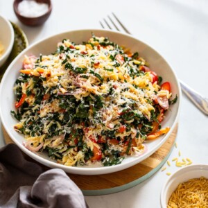 delicious orzo kale salad serving in white bowl on white countertop