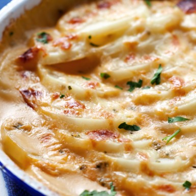 Cheesy scalloped potatoes in an old blue enamel bowl.