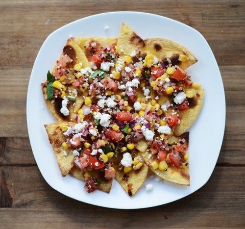 Healthy Quinoa Nachos on a white plate sitting on a wood kitchen table.