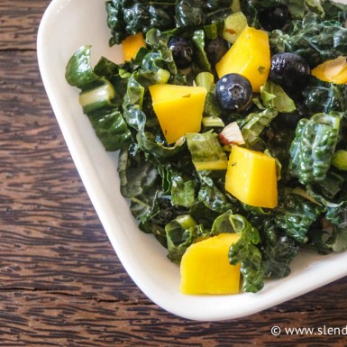 a white platter with kale salad mango and blueberries