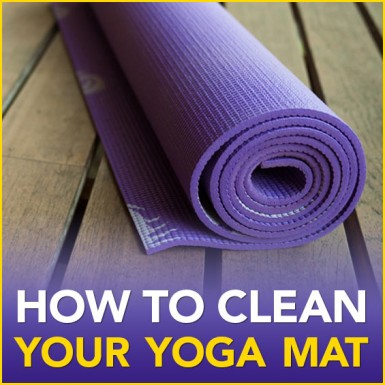 A purple rolled up yoga mat on a wood floor with the words "How To Clean Your Yoga Mat"