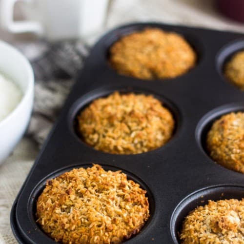 Coconut Almond Muffins in a muffin pan sitting on a kitchen counter.