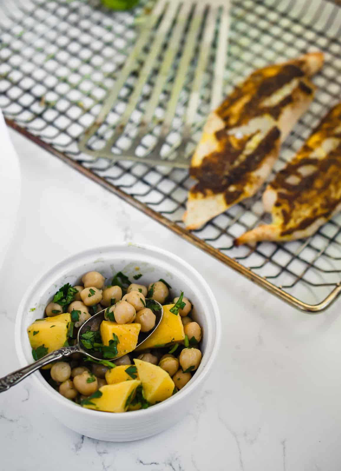 Bowls of mango chickpea salsa with grilled tilapia on grill pan