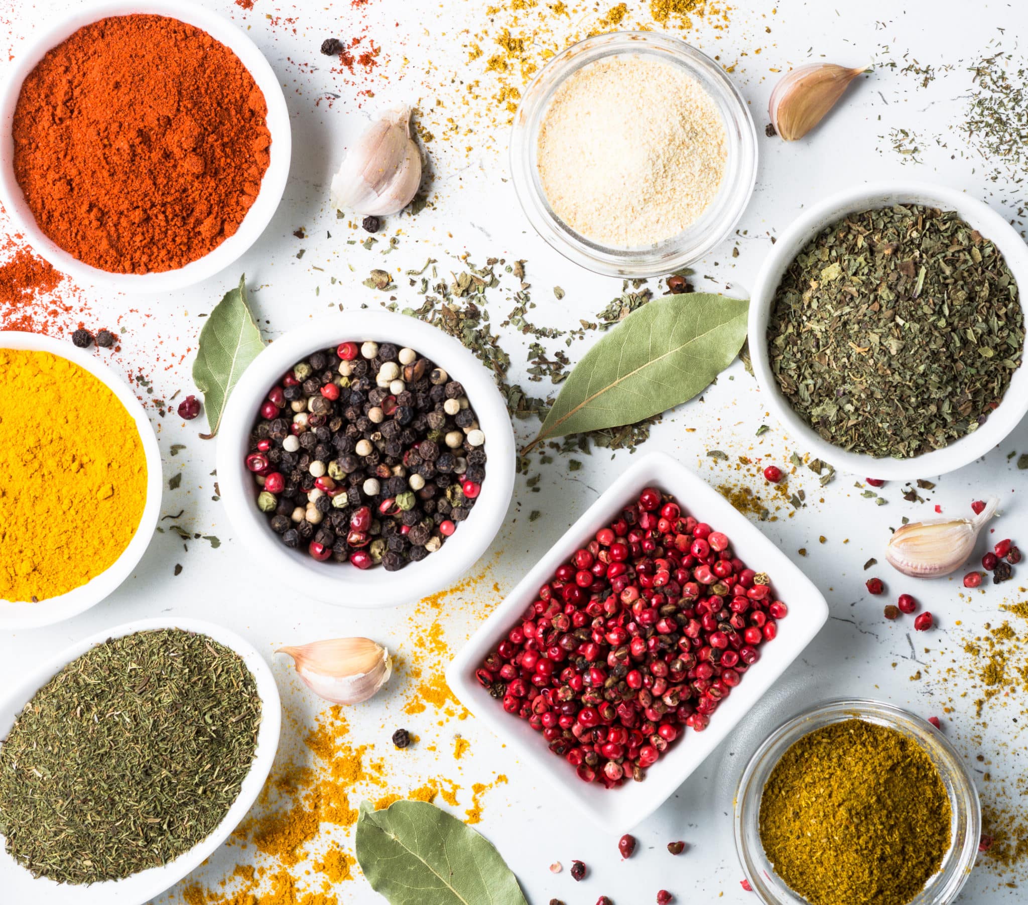 Variety of spices in individual dishes on white background