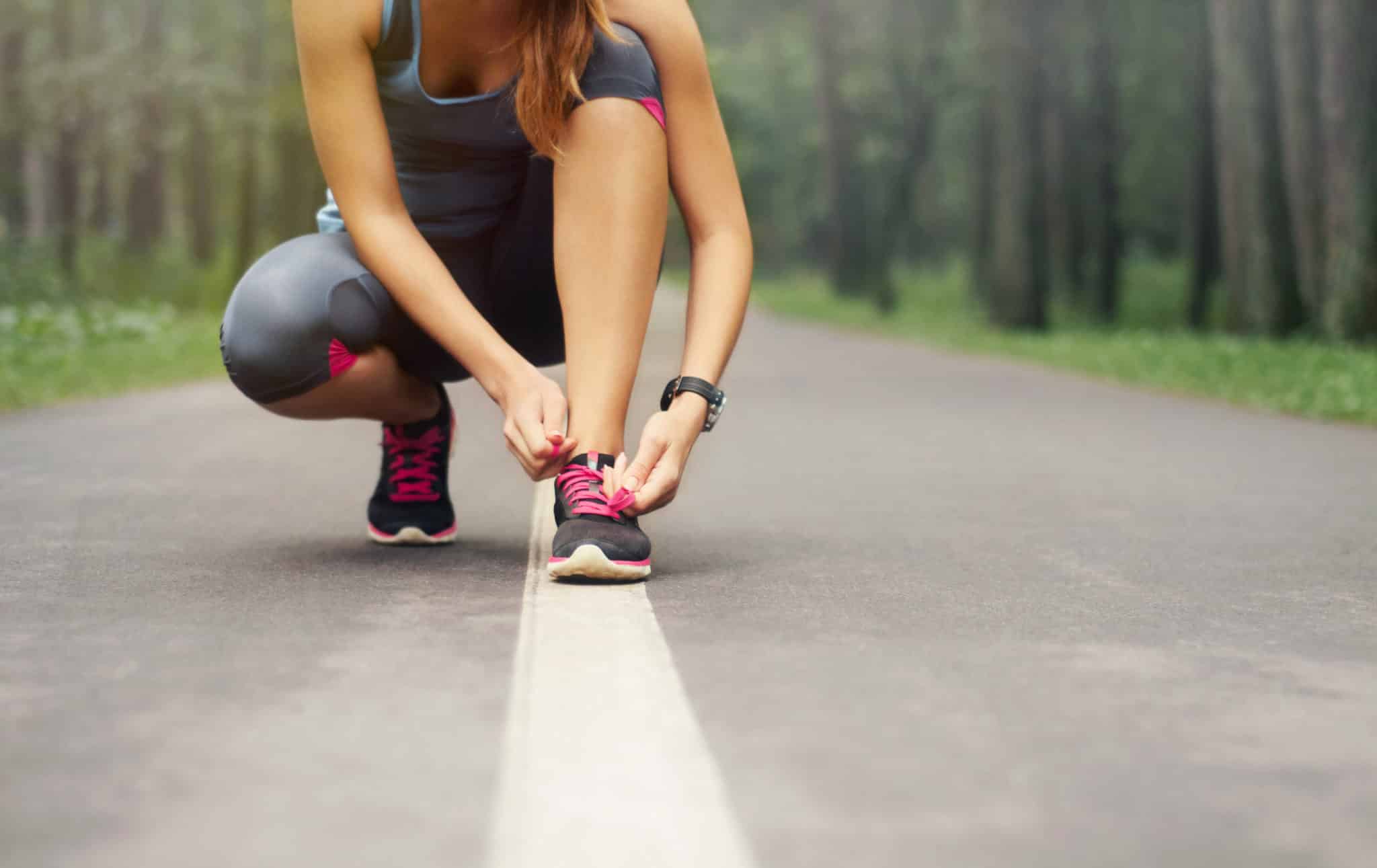 A woman lacing up her running shoes.