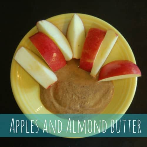 A plate of cut up apples and almond butter to dip them in