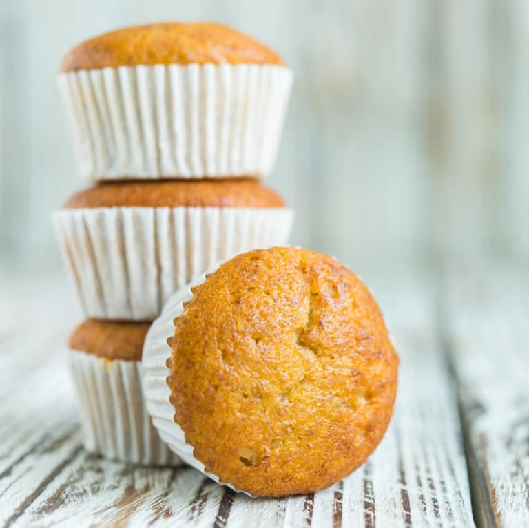 Gluten free banana bread muffins in a stack with blue background