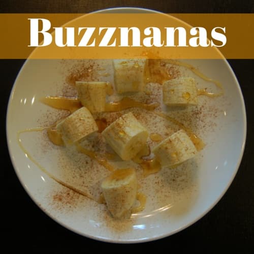 A white plate with banana chunks topped with drizzled honey and sprinkled with cinnamon