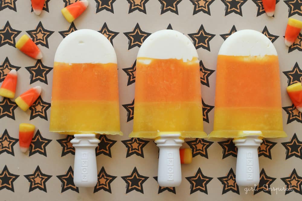 Three Candy Corn Popsicles on a platter with a black and orange star pattern.