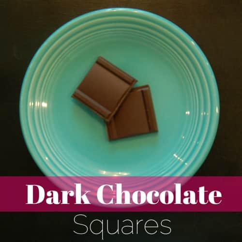 a plate with 2 squares of dark chocolate on it