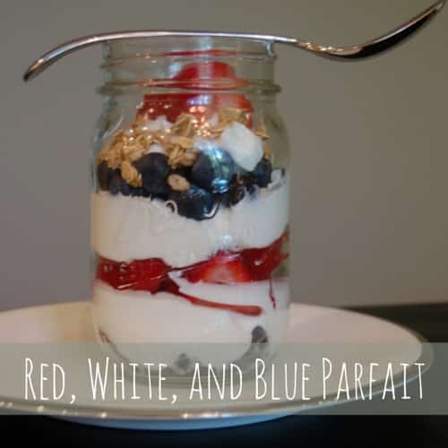 A yogurt smoothie in a mason jatr layered yogurt, strawberries, blue berries , and granola.