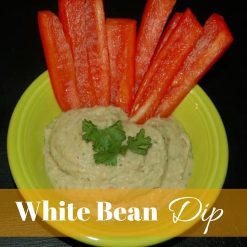 A plate of homemade white bean dip and fresh red pepper cut up to eat it with