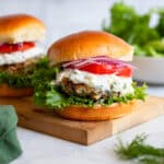 greek turkey burgers with toppings on wooden serving board on white counter