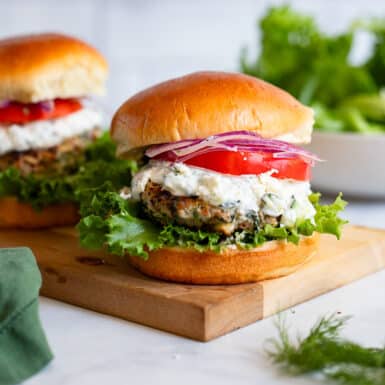 greek turkey burgers with toppings on wooden serving board on white counter