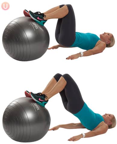 Chris Freytag performing a lift and lower exercise on stability ball wearing black yoga pants and a blue top.