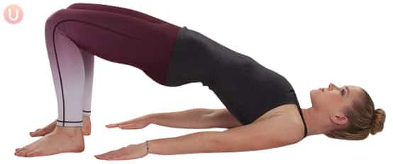 Chloe Freytag demonstrating Bridge Pose in a black tank top and yoga pants