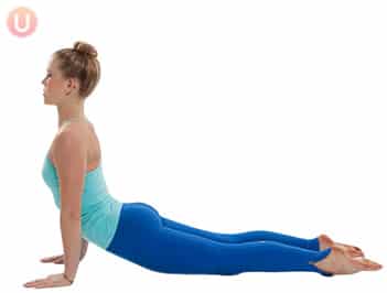 Chloe Freytag demonstrating Cobra pose in a blue tank top and yoga pants