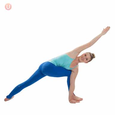 Chloe Freytag demonstrating a revolved extended side angle with open arms in a blue tank top and yoga pants