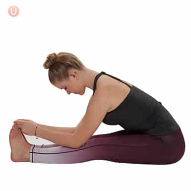 Chloe Freytag demonstrating a Seated Forward Fold in a black tank top and yoga pants