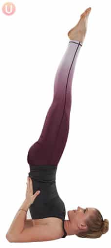 Chloe Freytag demonstrating Shoulder Stand Pose in a black tank top and yoga pants