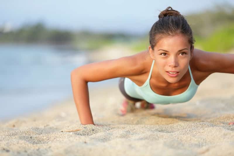a woman doing push-ups in the sand