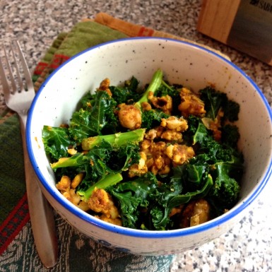 A white bowl with blue rim filled with pumpkin kale curry.
