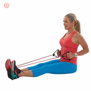 Chris Freytag demonstrating a resistance band row wearing a red top and blue exercise pants