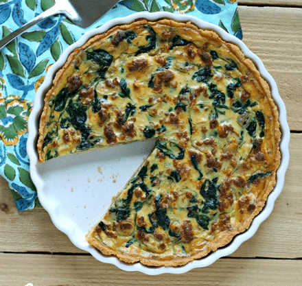 Chorizo and Spinach Quiche in a quiche pan on a wooden table.