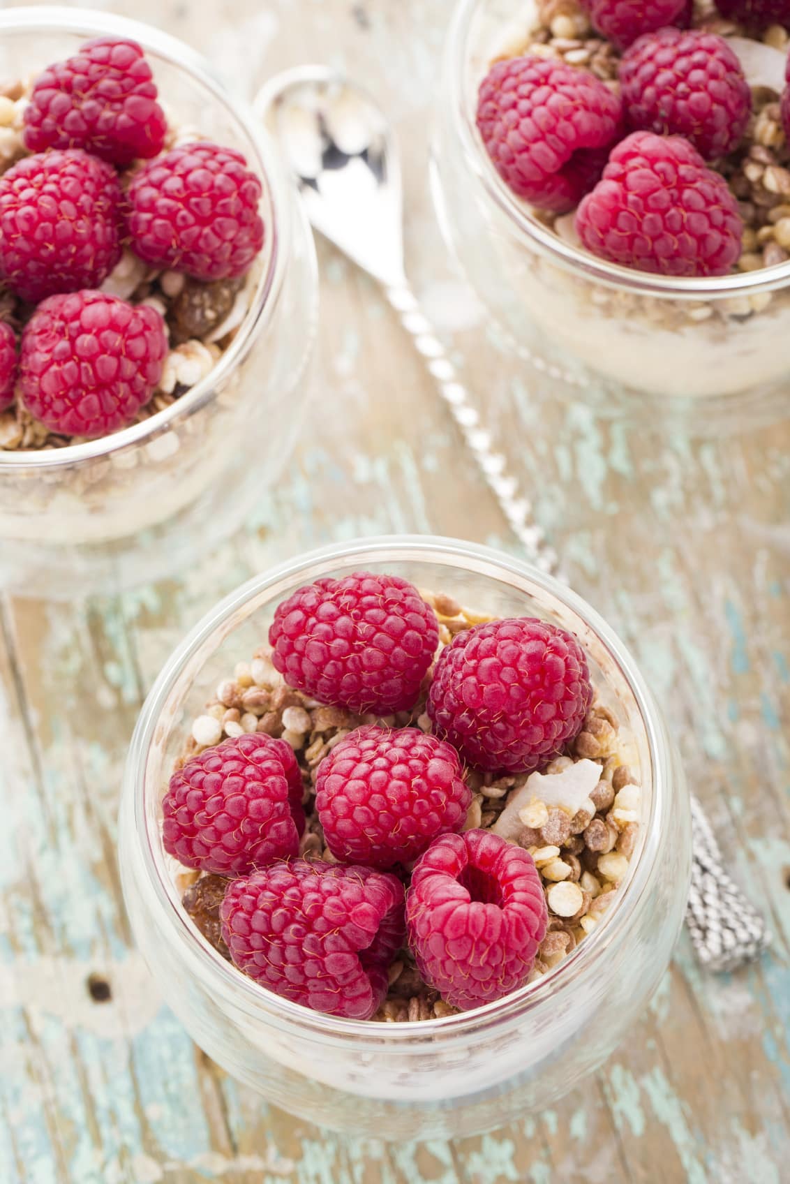 3 clear bowls of Vanilla Raspberry Overnight Oats on a wooden table.