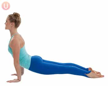 Chloe Freytag demonstrating an Upward Dog in a blue tank top and yoga pants