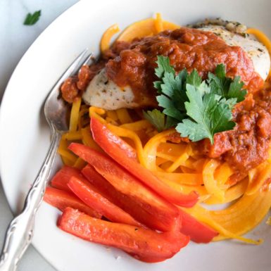 Butternut squash noodles with chicken and red pepper in a cream colored bowl