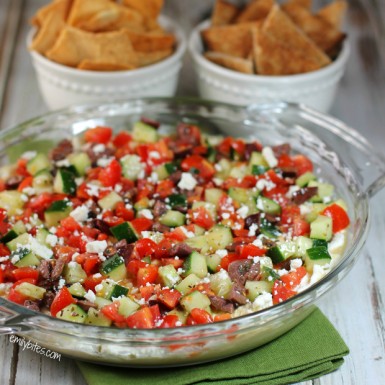 Greek Layer Dip with tomatoes, cucumber, feta, and hummus.