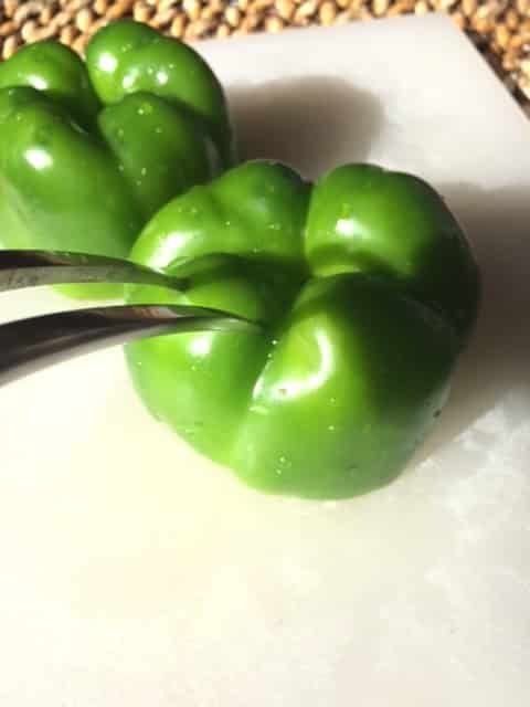 A green pepper being poked with a fork.