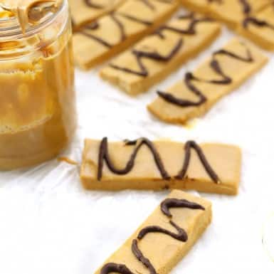 Healthy No-Bake Peanut Butter Cup Protein Bars on a kitchen table with a jar of peanut butter