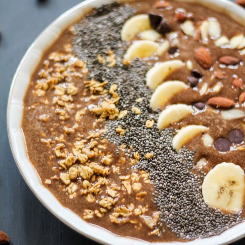 The mocha banana protein smoothie bowl topped with bananas, granola, carob chips, nuts, and chia seeds.