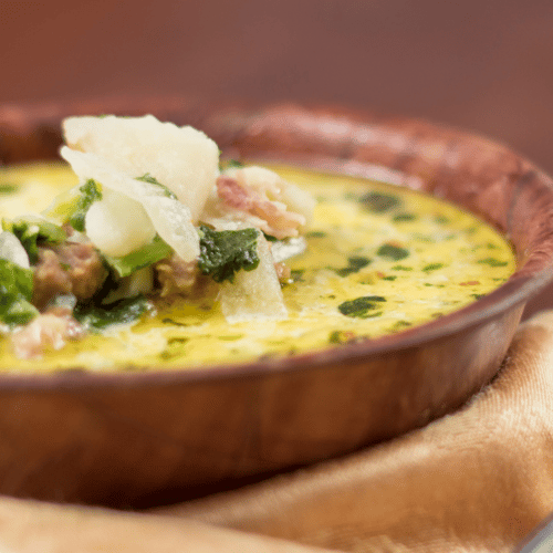 Wooden bowl of healthy zuppa toscana with parmesan on top