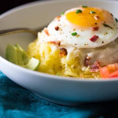 Dive into this delicious bowl of low-carb spaghetti squash topped with cauliflower Alfredo. bacon crumbles, and a tasty egg!