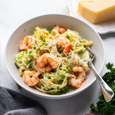 prepared serving of healthy shrimp alfredo in bowl on white counter