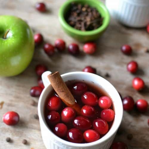 Throwing a holiday party? Make this crock pot spiced cranberry apple cider recipe for a SUPER easy and festive holiday beverage.