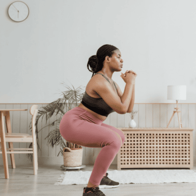 woman in pink legging doing a workout squat in her home
